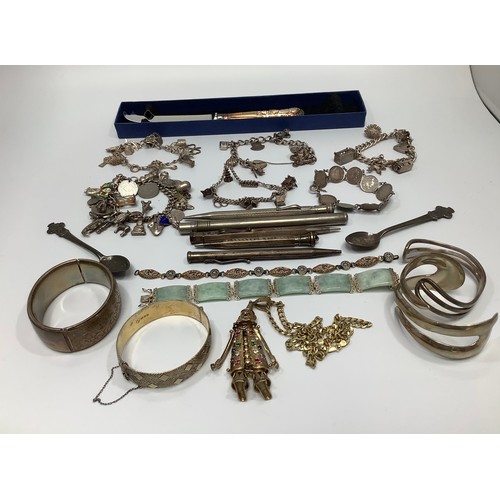 66 - A small collection of assorted silver items comprising various charm bracelets and bangles, propelli... 