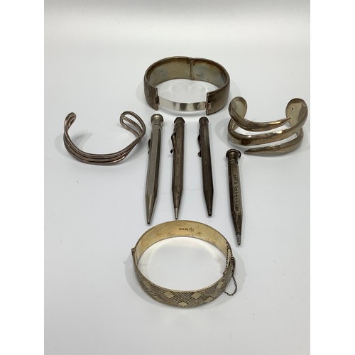 66 - A small collection of assorted silver items comprising various charm bracelets and bangles, propelli... 