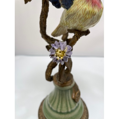 461 - A pair of bronze figural candlesticks by Mark Roberts, with colourful porcelain birds perched on twi... 