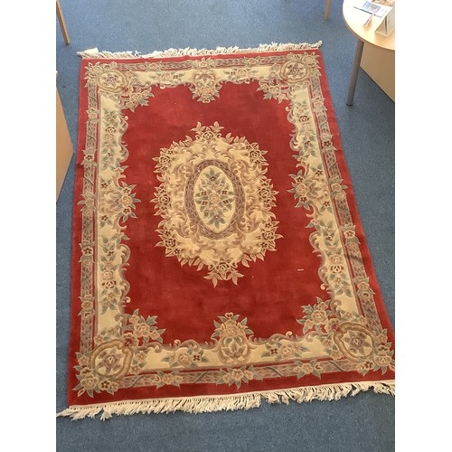 472 - A large Oriental Eastern Kayam rug with central cream, green and brown floral medallion to red groun... 