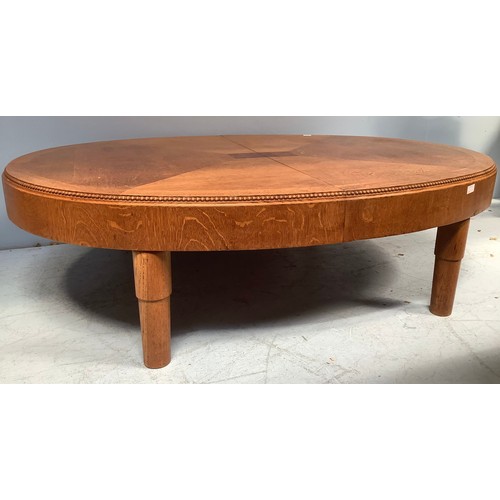 568 - An oak veneered coffee table, of oval form, in two halves with fastenings to underside, beaded top e... 