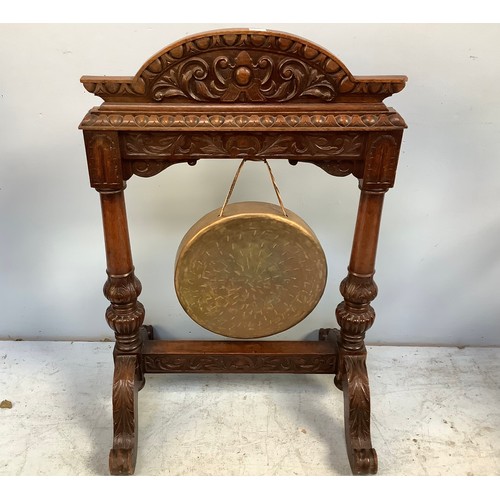 574 - A carved oak framed floor-standing dinner gong, with foliate carved arched top, raised on scrolled s... 