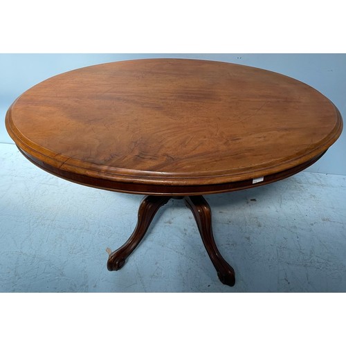 604 - A small oval dining table raised on central turned column to four scrolled feet with castors, 120cm ... 