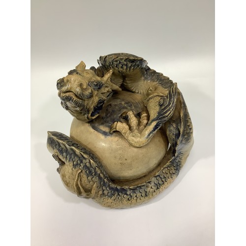 75 - A 19th century Japanese glazed clay figure of a dragon with its body wrapped round a pearl or egg?, ... 