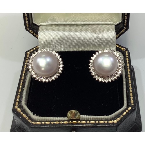 262 - A pair of 18ct white gold, pearl and diamonds earrings, each centrally set with a large pearl and su... 