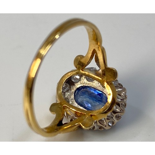 273 - An 18ct gold ring, centrally claw set with an oval faceted sapphire coloured stone, surrounded by te... 