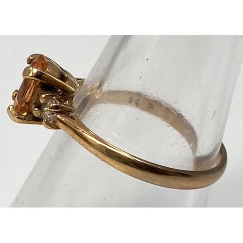 277 - A 9ct gold ring centrally four claw set with an oval faceted citrine coloured stone, flanked by two ... 