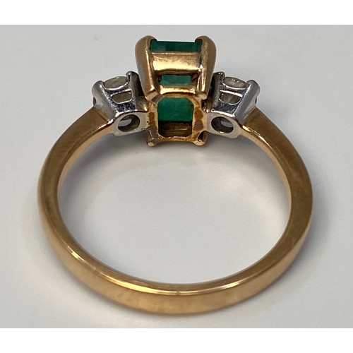 274 - A 9ct gold three stone ring, centrally four claw set with an emerald 'cut' emerald 'coloured' stone,... 