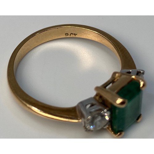 274 - A 9ct gold three stone ring, centrally four claw set with an emerald 'cut' emerald 'coloured' stone,... 