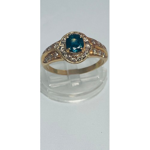 194 - An 18ct yellow gold dress ring, set with an oval blue faceted stone to the centre with 14 x small di... 