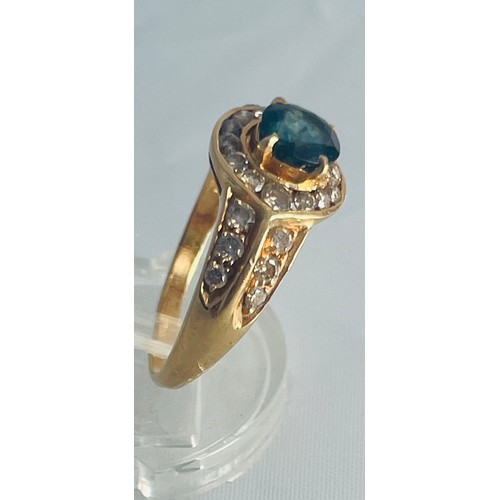 194 - An 18ct yellow gold dress ring, set with an oval blue faceted stone to the centre with 14 x small di... 