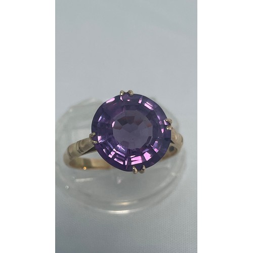 195 - A 14ct yellow gold dress ring, set with round purple coloured faceted stone, ring weighs 3.9 grams, ... 