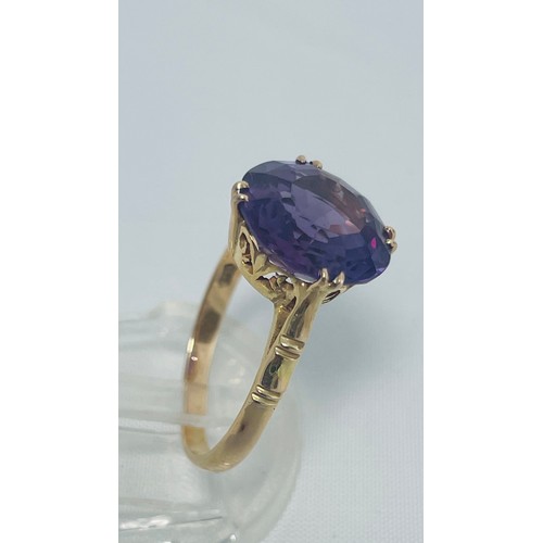 195 - A 14ct yellow gold dress ring, set with round purple coloured faceted stone, ring weighs 3.9 grams, ... 