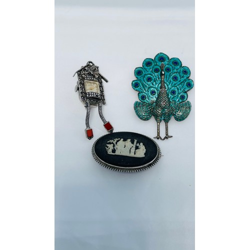 207 - Three silver brooches, one styled as a peacock, one a marcasite set cuckoo clock watch, and one an o... 