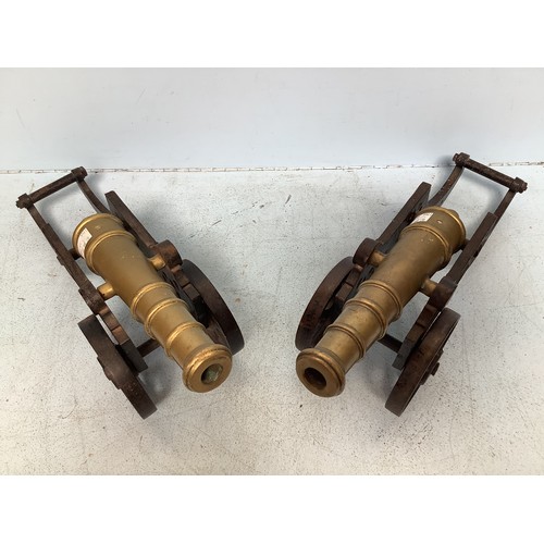 374 - A pair of brass cannons raised on cast iron bases, cannons 30cm, overall 45cm