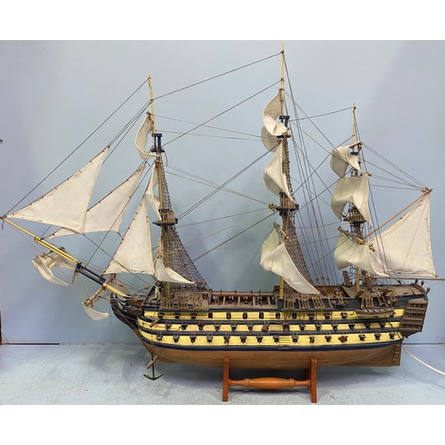 571 - A large hand built model of HMS Victory fully rigged with Nelson standing on the bow, raised on wood... 