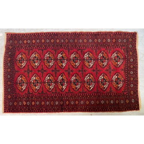 616 - A Caucasian hand-knotted woollen carpet, the central claret field with rows of guls, and a continuou... 