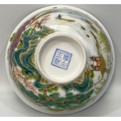 38 - A Chinese porcelain bowl hand painted with a scene of a figure of a man on a raft with houses, trees... 