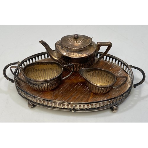 176 - An Edwardian Four-Piece Miniature teaset, comprising teapot, sugar and cream jug on oval pierced gal... 