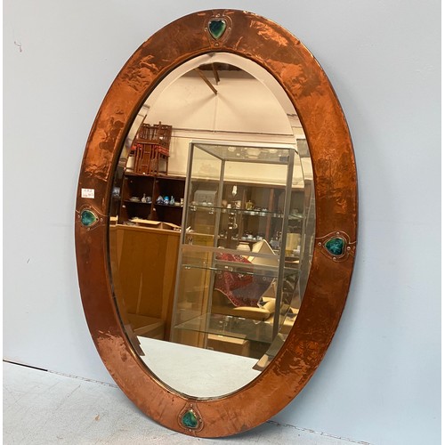 615 - A Liberty & Co Arts & Crafts oval mirror with hammered copper frame, inset with heart shaped pottery... 