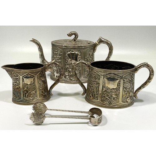 183 - A Chinese Export Silver Three-Piece Silver Teaset by Wang Hing, of tapering oval section, richly emb... 