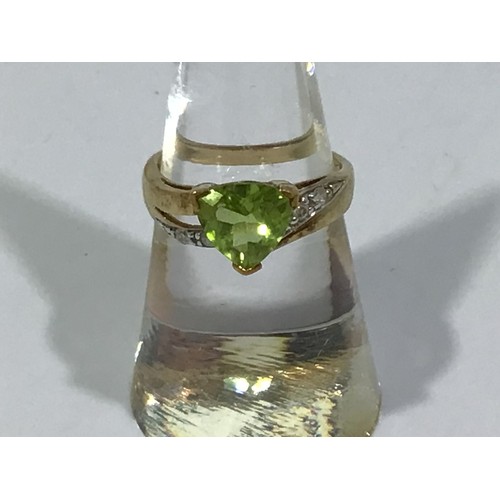 293 - A 9ct gold Peridot and diamond ring, centrally three-claw-set with a trilliant cut peridot, flanked ... 