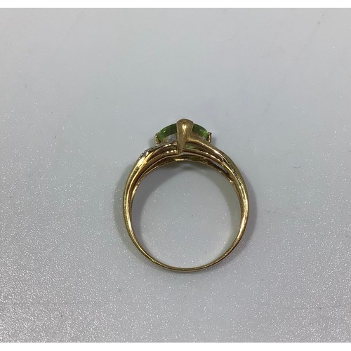 293 - A 9ct gold Peridot and diamond ring, centrally three-claw-set with a trilliant cut peridot, flanked ... 