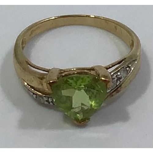 293 - A 9ct gold Peridot and diamond ring, centrally three-claw-set with a trilliant cut peridot, flanked ... 