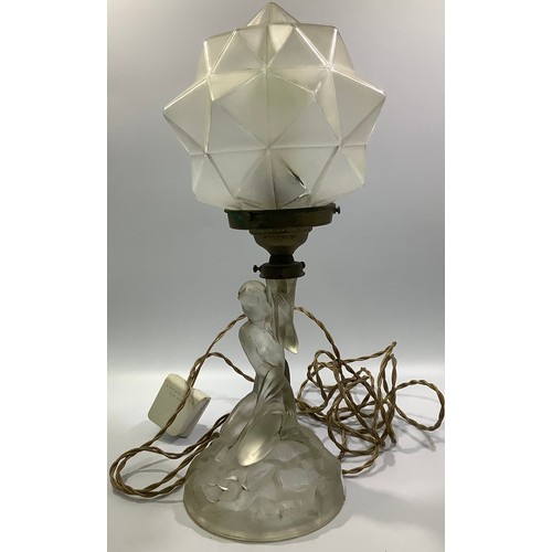 614 - An Art Deco lamp with a clear glass nude female kneeling on a naturalistic circular base, holding al... 