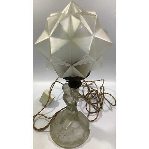 614 - An Art Deco lamp with a clear glass nude female kneeling on a naturalistic circular base, holding al... 