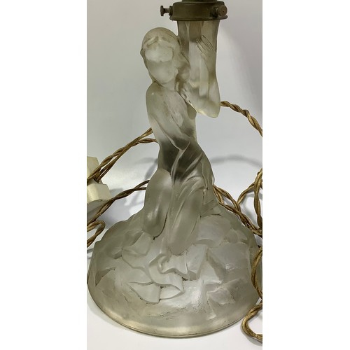 614 - An Art Deco lamp with a clear glass nude female kneeling on a naturalistic circular base, holding al... 