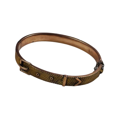 318 - A 9ct gold bangle, designed as a buckle to the top, with safety chain, weighs 10.9 grams.

The top o... 