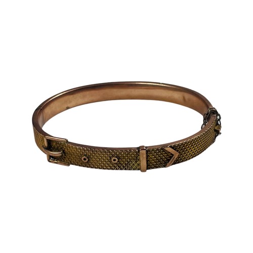 318 - A 9ct gold bangle, designed as a buckle to the top, with safety chain, weighs 10.9 grams.

The top o... 