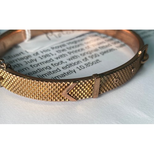 318 - A 9ct gold bangle, designed as a buckle to the top, with safety chain, weighs 10.9 grams.

The top o... 