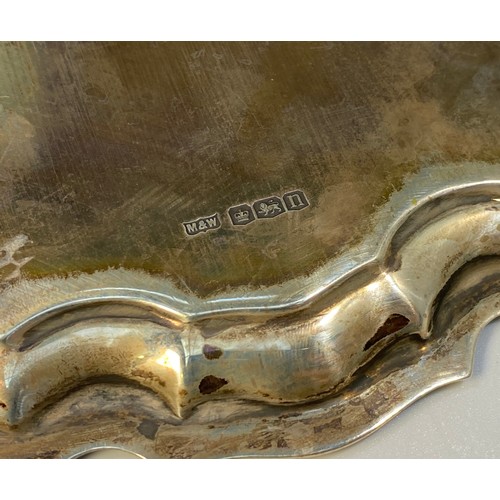 134 - A silver salver with shaped rim, inscription to centre, raised on three pad feet, Sheffield, 1930, m... 