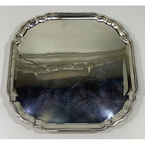 162 - A ERII silver salver of square form with serpentine canted corners, pie-crust rim raised on four scr... 
