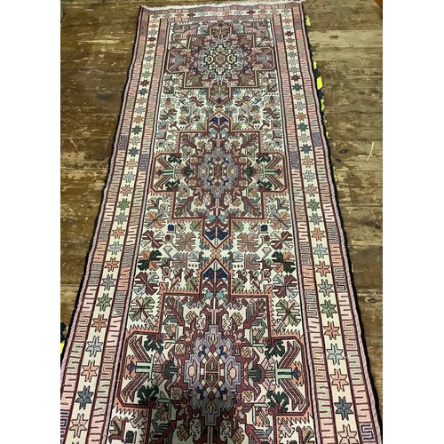 588 - A long woollen hand-knotted runner with geometric designs to cream ground, 300 x 83cm