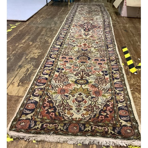 587 - A long woollen hand-knotted runner decorated with flowers to cream ground, 360 x 65cm