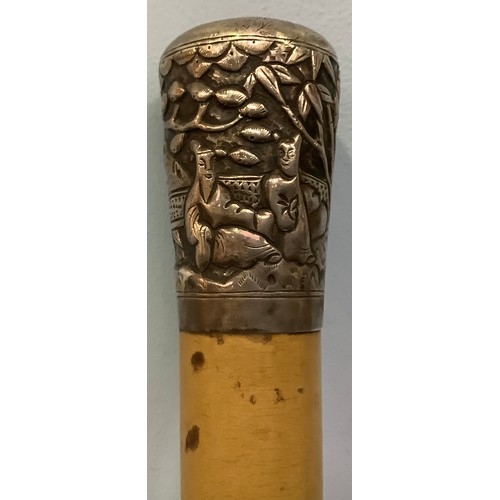 392 - A white metal (tests as silver) topped walking stick, pommel decorated with continuous moulded relie... 