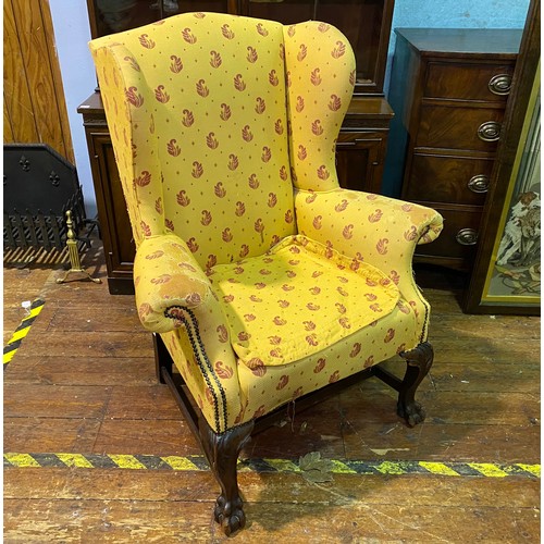 635 - A Victorian wingback armchair, with yellow and red fabric upholstery and studding, raised on carved ... 