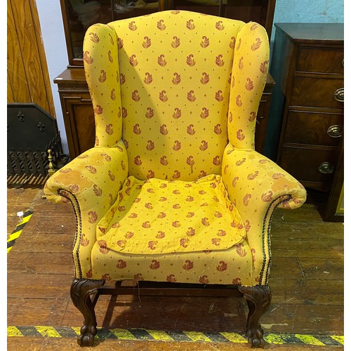 635 - A Victorian wingback armchair, with yellow and red fabric upholstery and studding, raised on carved ... 