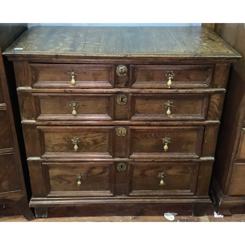 633 - A 17th century oak chest of four long, graduated drawers with panelled fronts, brass drop pulls and ... 