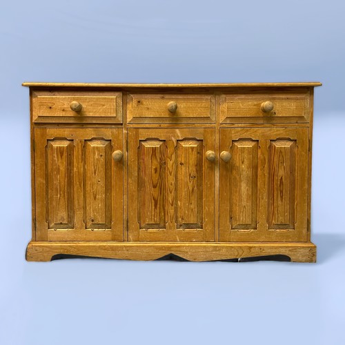 492 - A pine dresser base, the frieze with three short drawers, above three panelled cupboard doors, raise... 