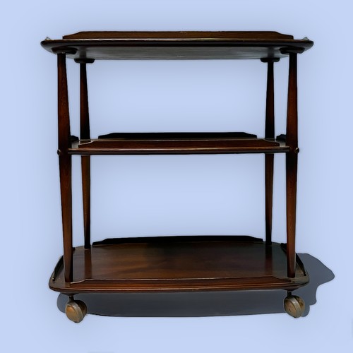 491 - A 20th century Ercol dark elm three-tier serving trolley, each tier with gallery and raised on turne... 