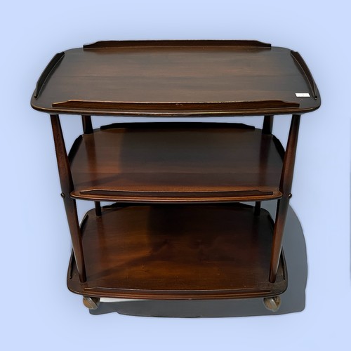 491 - A 20th century Ercol dark elm three-tier serving trolley, each tier with gallery and raised on turne... 