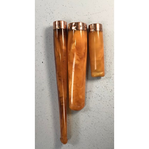 329 - Three various amber cheroot holders, each with 9ct gold banded ends, in fitted cases