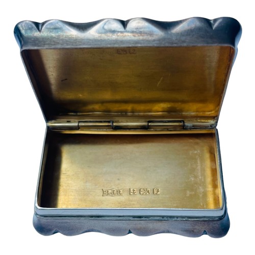 180 - A silver and silver gilt serpentine-rectangular pill box with hinged cover, top mounted with the fea... 