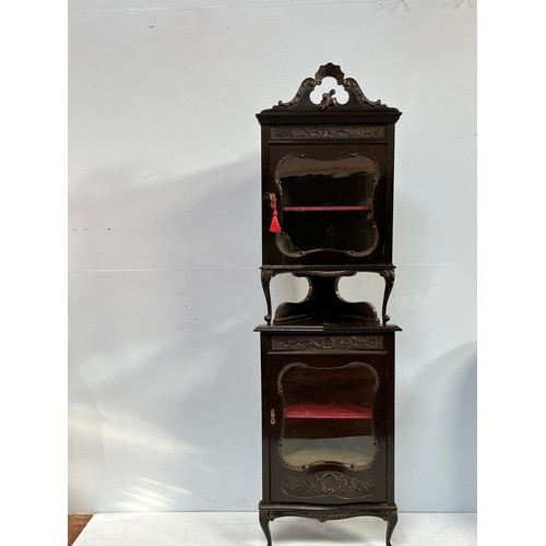 511 - An ebonised corner display cabinet, carved and pierced cornice atop a glazed door enclosing lined sh... 