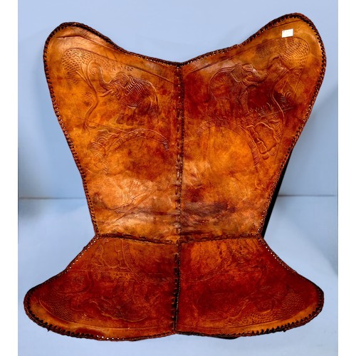 516 - A leather butterfly chair, brown stitched slung leather cover decorated with embossed elephants, ove... 