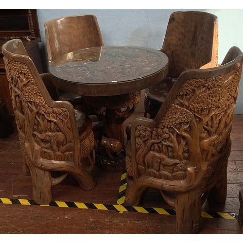 515 - An African carved solid wooden table and four chairs, probably Acacia wood, the solid chairs and tab... 